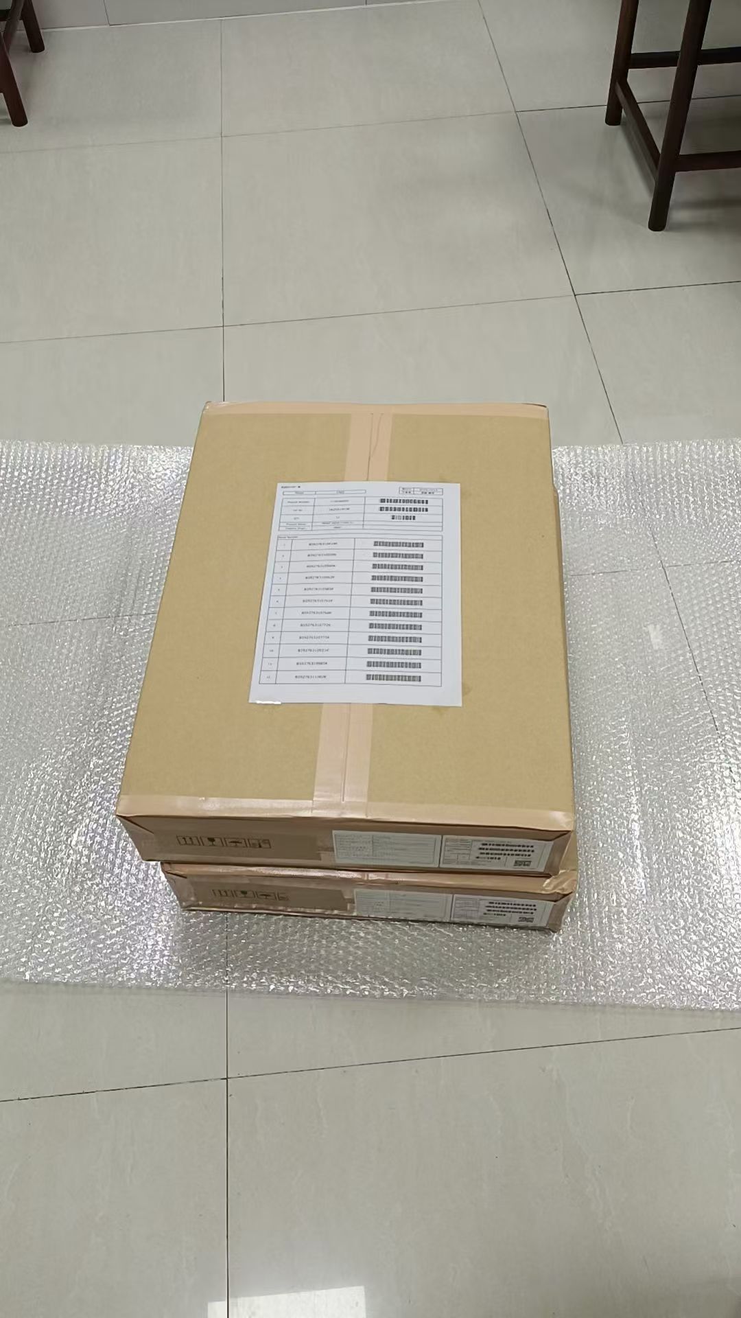 Stack of cardboard boxes on a bubble wrap sheet, with a printed packing list on top.