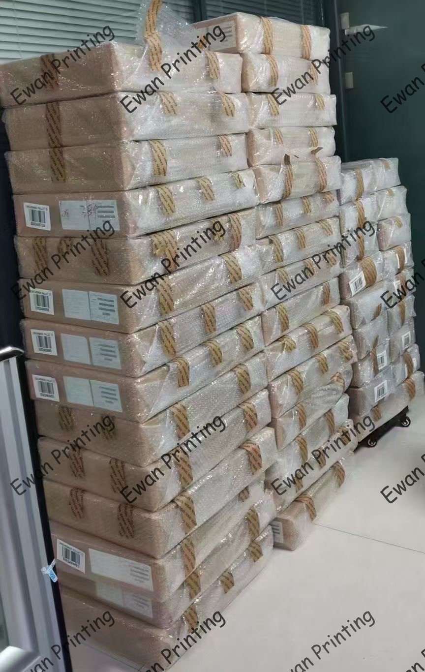 A neatly stacked pile of wrapped packages labeled for printing, arranged against a wall.